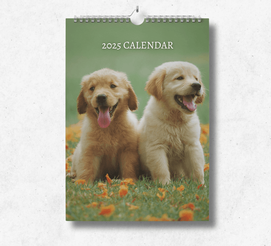 2025 Puppy Calendar featuring two adorable golden labrador puppies sitting on the grass with their tongues out panting.